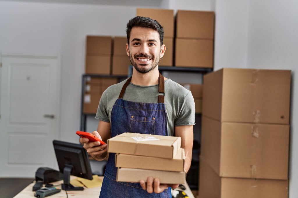Young businessperson with packaging and mobile phone